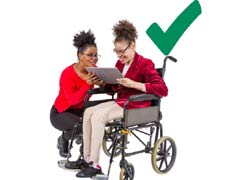 woman helps woman in wheelchair with tablet