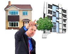 A man in a suit is standing in front of images of two buildings. One is a house, the other is a block of units. He is pointing at the block of units. He is indicating choosing the units.