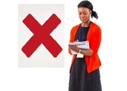 A woman in a black dress and red cardigan is holding a notebook. She is writing in it. There is a red cross beside her.